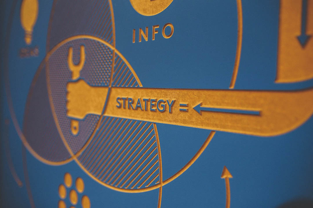 A blue wood-cut board with etched graphics and the word "strategy"